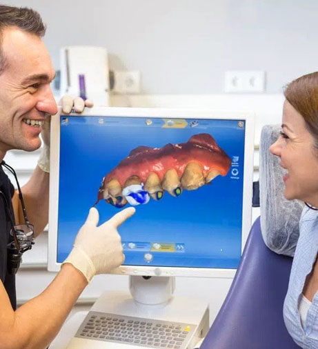 Dentist showing patient digital X-ray of tooth on computer screen in dental office.