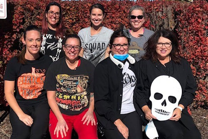 Fremont Dental Group team members posing together against decorative red foliage backdrop wearing casual attire.