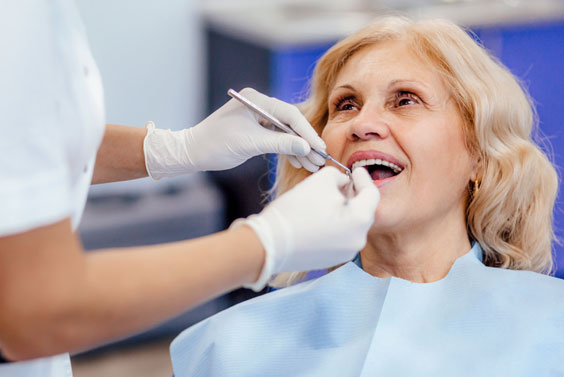 Dentist examining patient's teeth during dental checkup in clinical office setting.