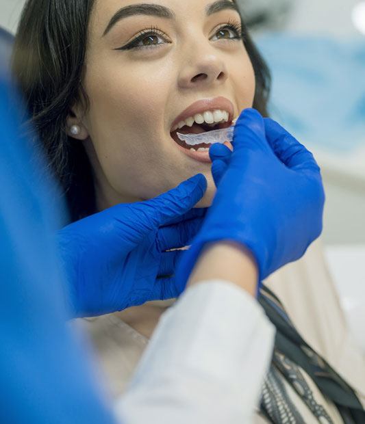 Dentist in blue gloves examining patient's teeth during dental checkup appointment.