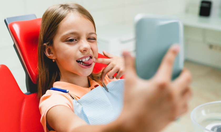 Young girl in dental chair taking selfie with tablet during dental visit.