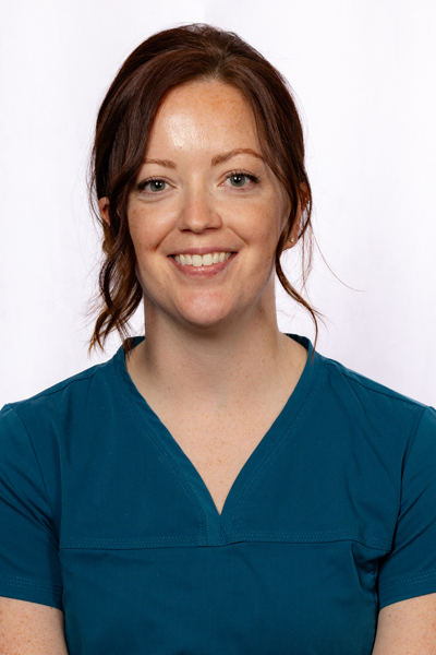 Smiling female dental professional in teal scrubs, professional headshot for Fremont Dental Group