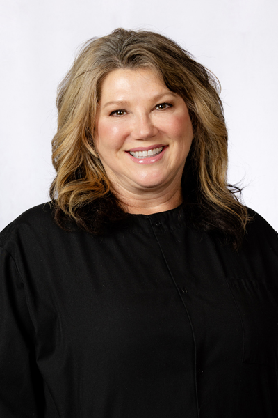 Professional headshot of smiling woman with wavy blonde hair wearing black shirt against white background.