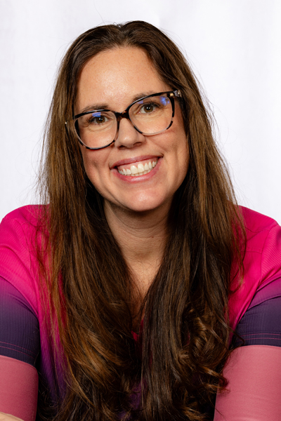 Woman with glasses smiling at camera, professional headshot for dental practice.