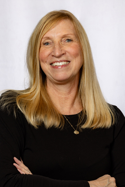Professional headshot of smiling woman with blonde hair wearing black top against white background.