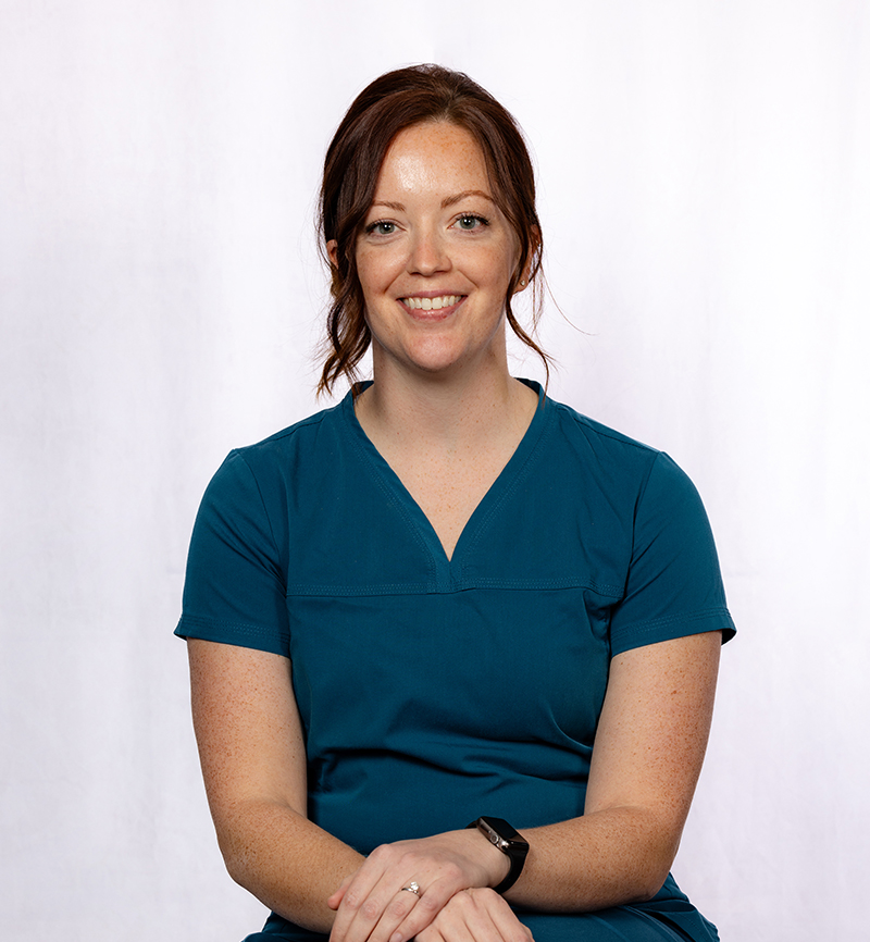 Professional woman in teal scrubs smiling at Fremont Dental Group, white background.
