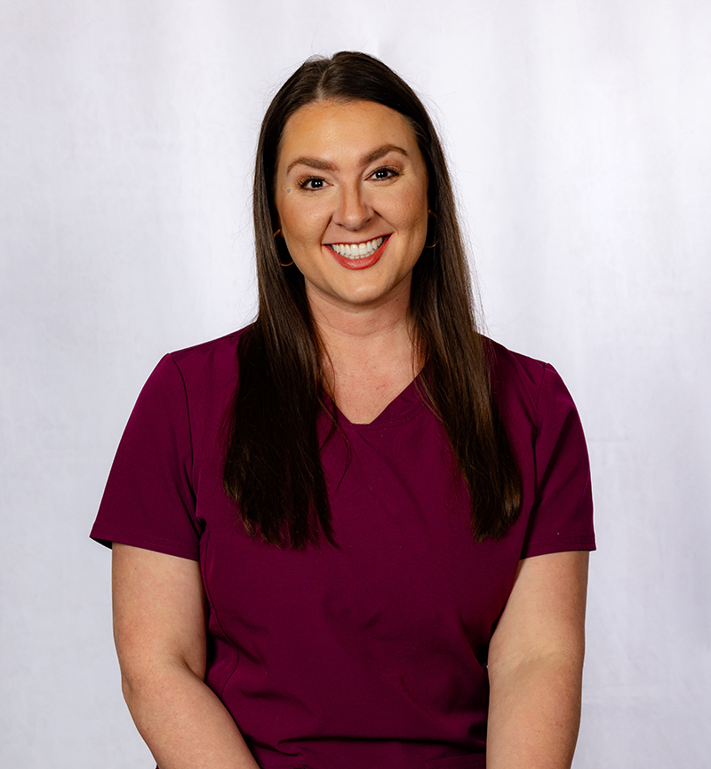 Professional headshot of smiling woman in maroon shirt against white background
