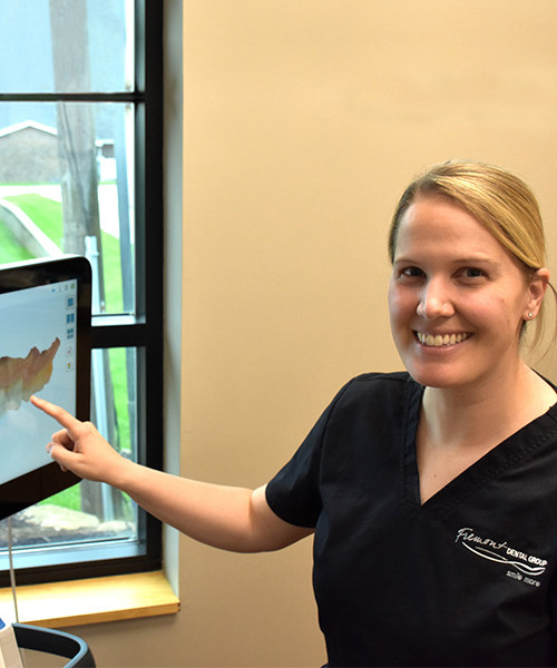 Dental professional smiling while pointing at aquarium display in modern dental office.
