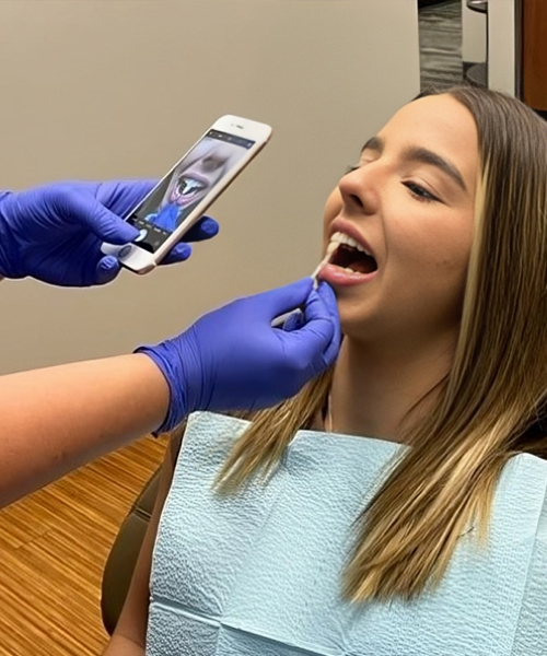 Dental patient receiving examination with intraoral camera in modern dental office setting.