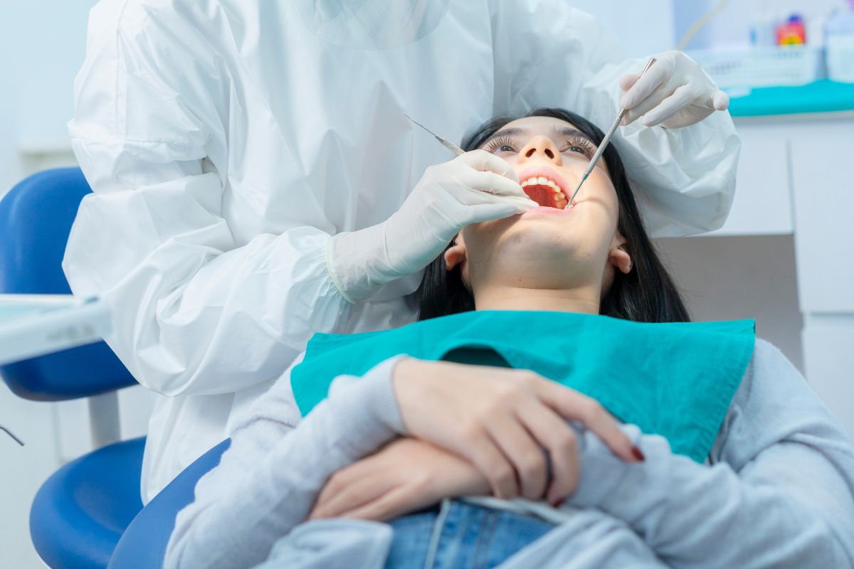 Dental hygienist examining a female patient's teeth during a routine checkup.