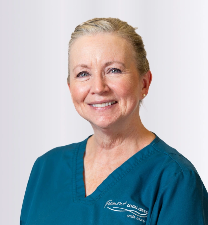 Professional headshot of female dental staff member wearing teal scrubs against white background.