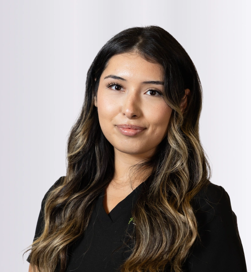 Professional headshot of woman with long dark hair wearing black top against white background.