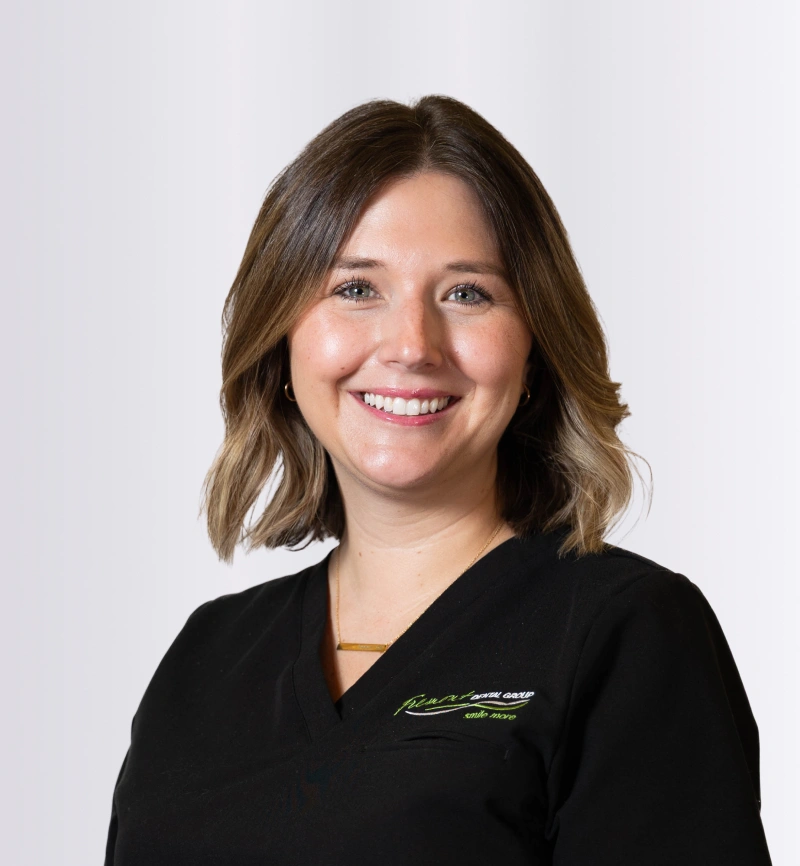 Professional headshot of smiling female dental staff member in black scrubs against white background.