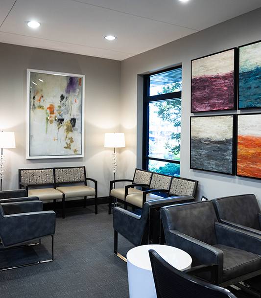 Modern dental office waiting room with contemporary furniture, artwork, and recessed lighting.
