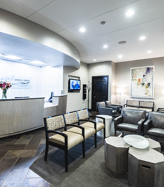 Modern dental office waiting room with comfortable seating, reception desk, and professional decor.