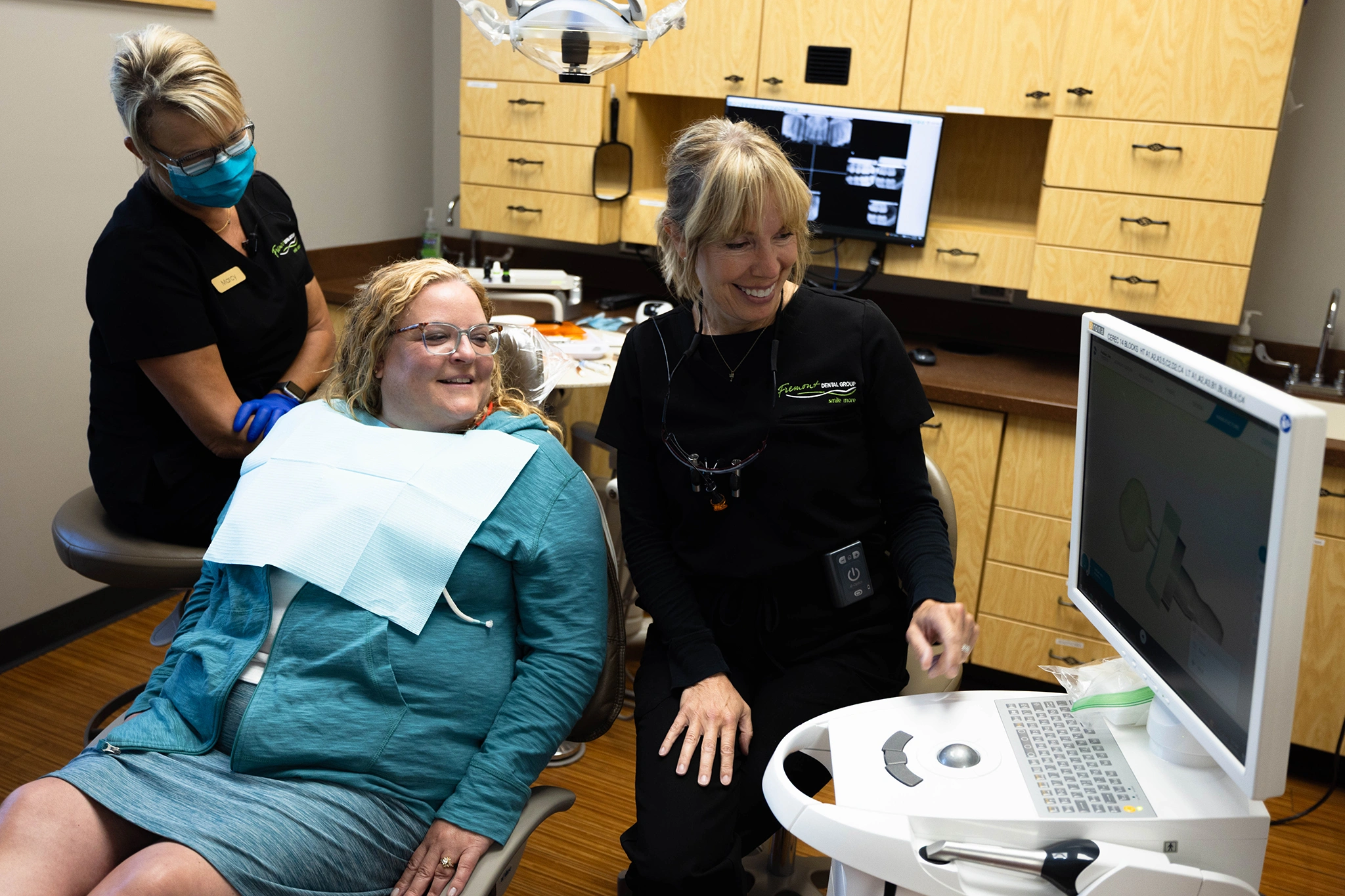 Dental patient receiving ultrasound examination from hygienist in modern dental office with equipment visible.