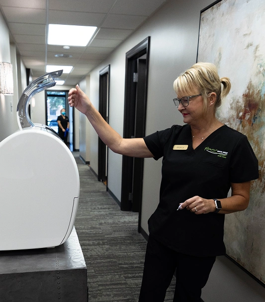 Dental professional demonstrating teeth whitening product in modern clinic hallway.