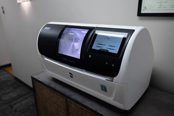 Dental laboratory analyzer machine with dual screens displaying test results in clinical setting.