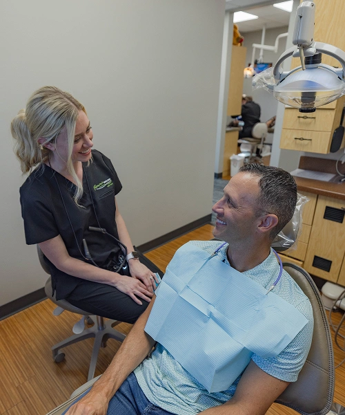 Dental hygienist examining male patient's arm in clinical treatment room at Fremont Dental Group.