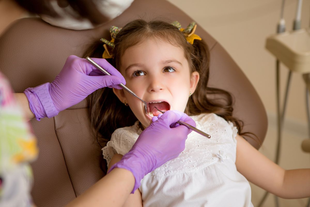 Pediatric dentist examining a child’s teeth during an early dental care appointment in a dental clinic.