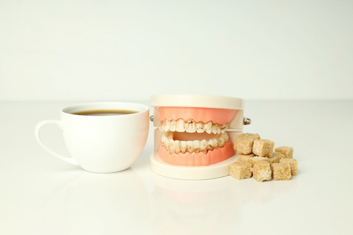 Dental model beside sugar cubes and a cup illustrating sugar’s impact on teeth and oral health.