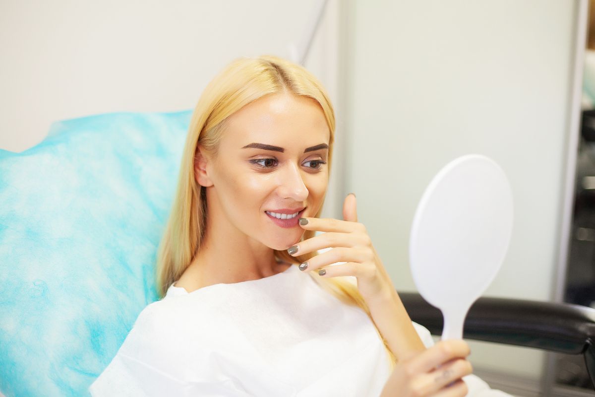 Patient admiring her smile after a cosmetic dentistry treatment during a dental consultation.